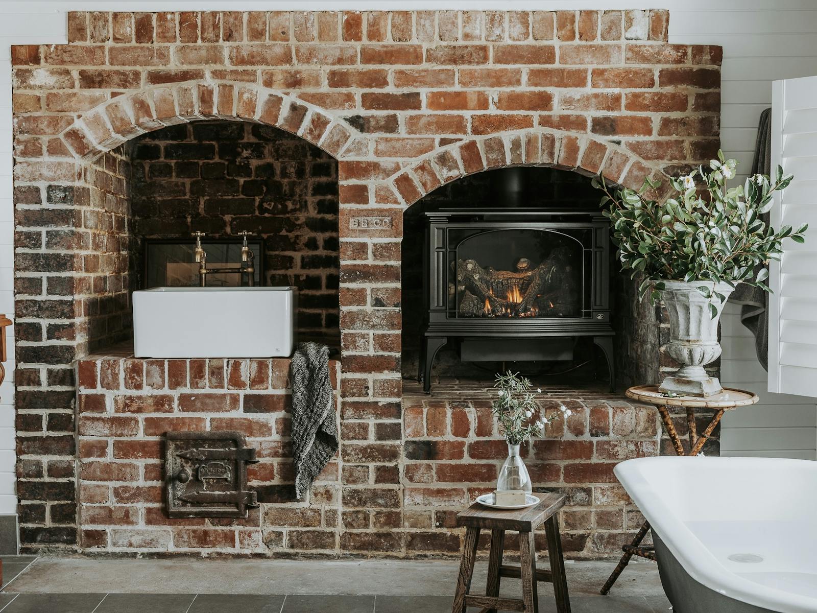 1800’s double brick fireplace renovated to accommodate bathroom sink and gas fire, claw foot bathtub