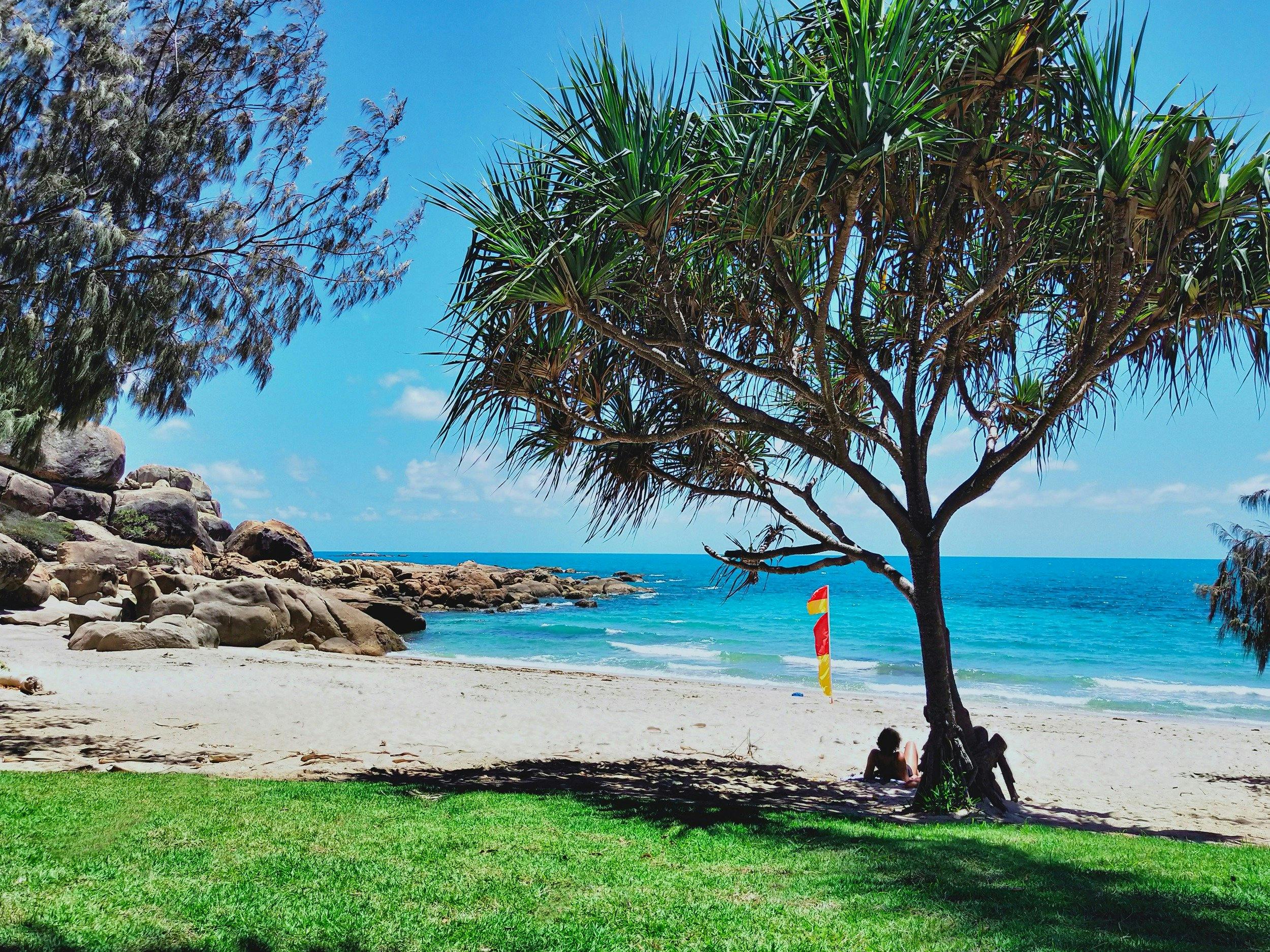People relaxing in shade at sandy beachfront