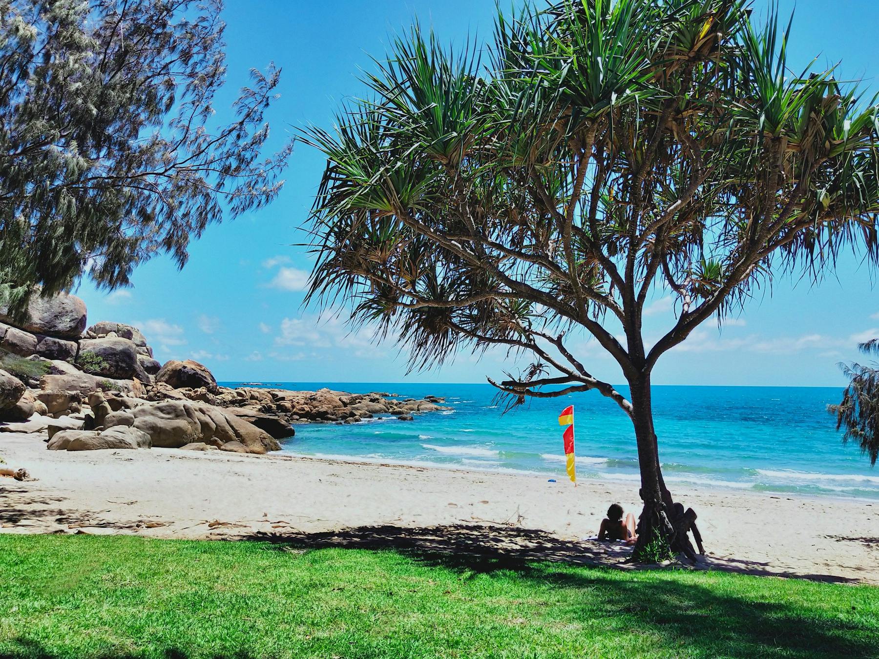 People relaxing in shade at sandy beachfront
