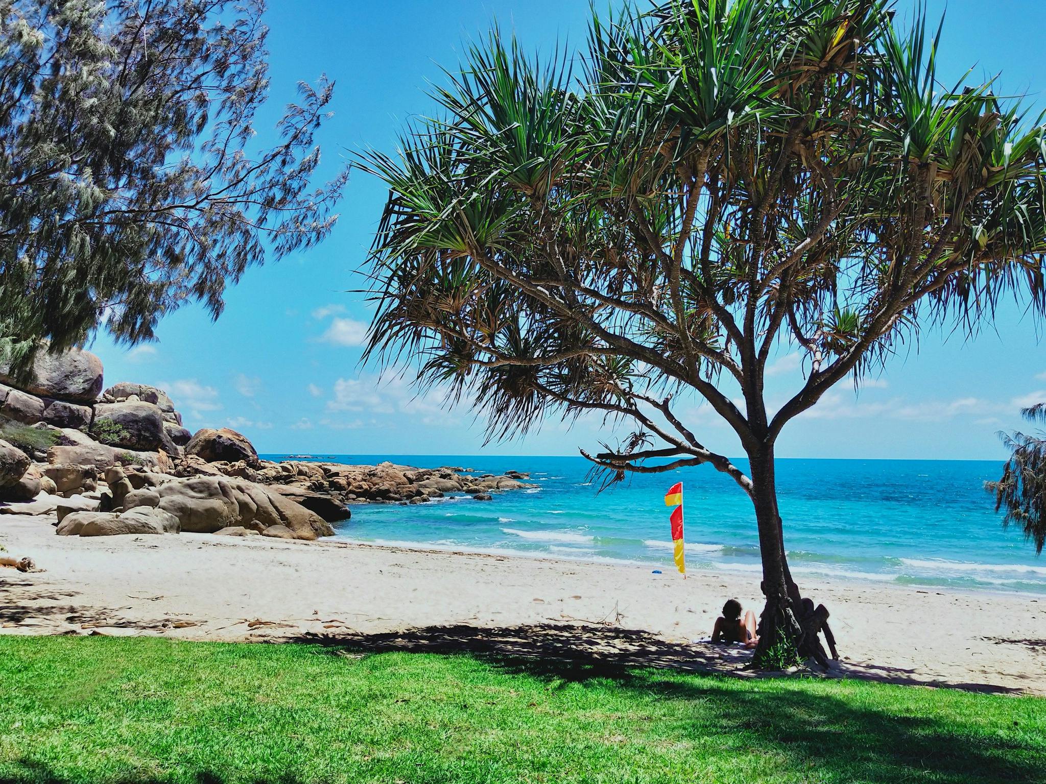 People relaxing in shade at sandy beachfront