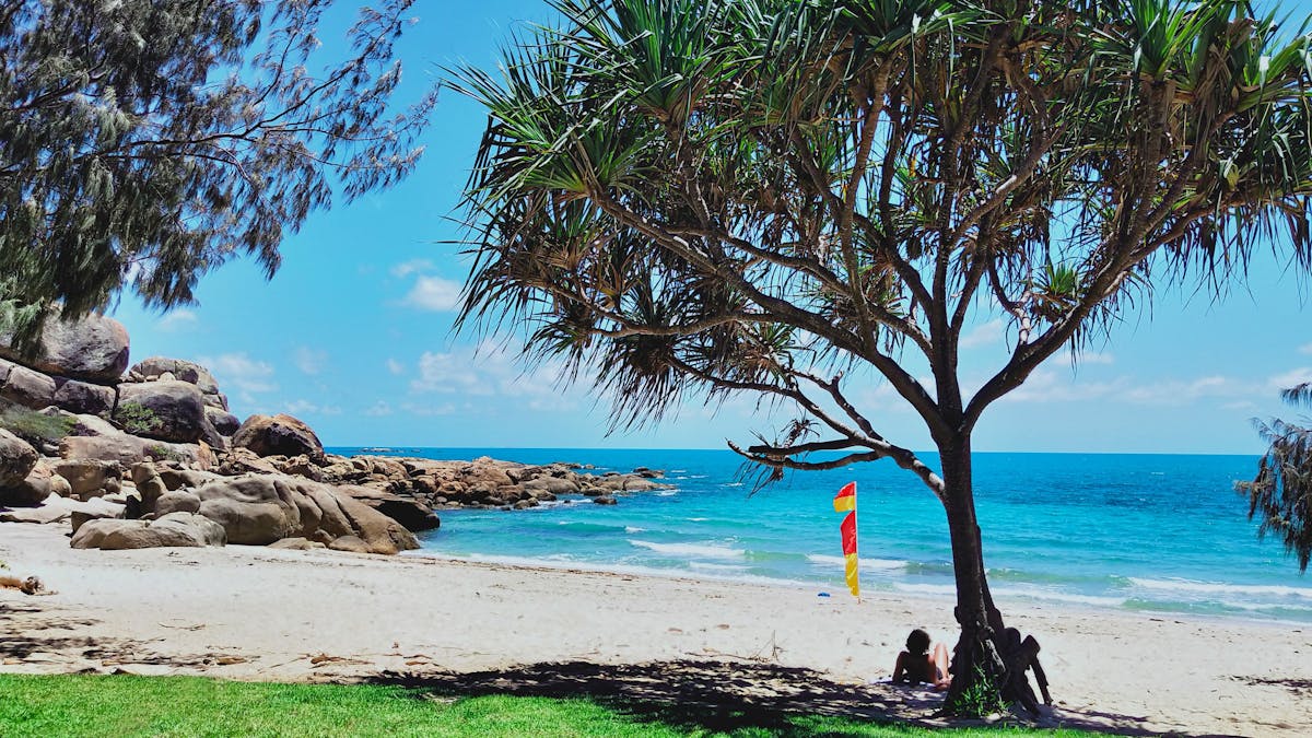 People relaxing in shade at sandy beachfront