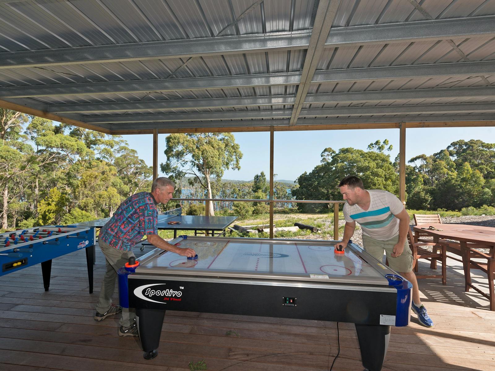 Two guys playing air hockey, Bruny Island Lodge games room