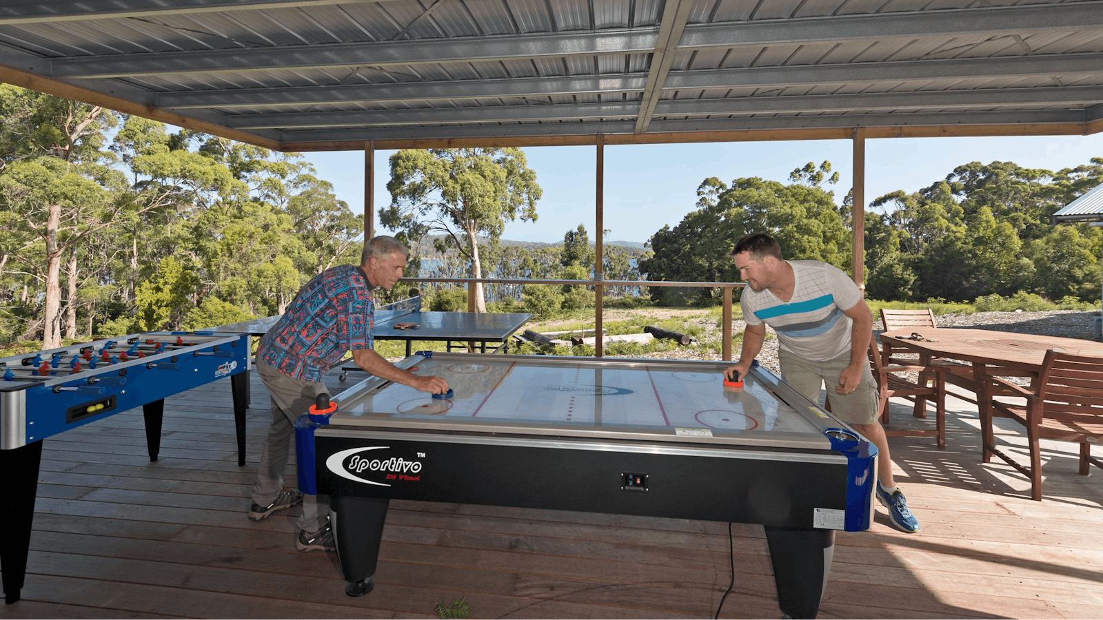 Two guys playing air hockey, Bruny Island Lodge games room