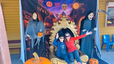 two women sitting in oversized chair with halloween figures beside