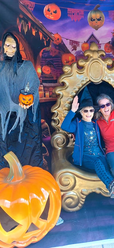two women sitting in oversized chair with halloween figures beside