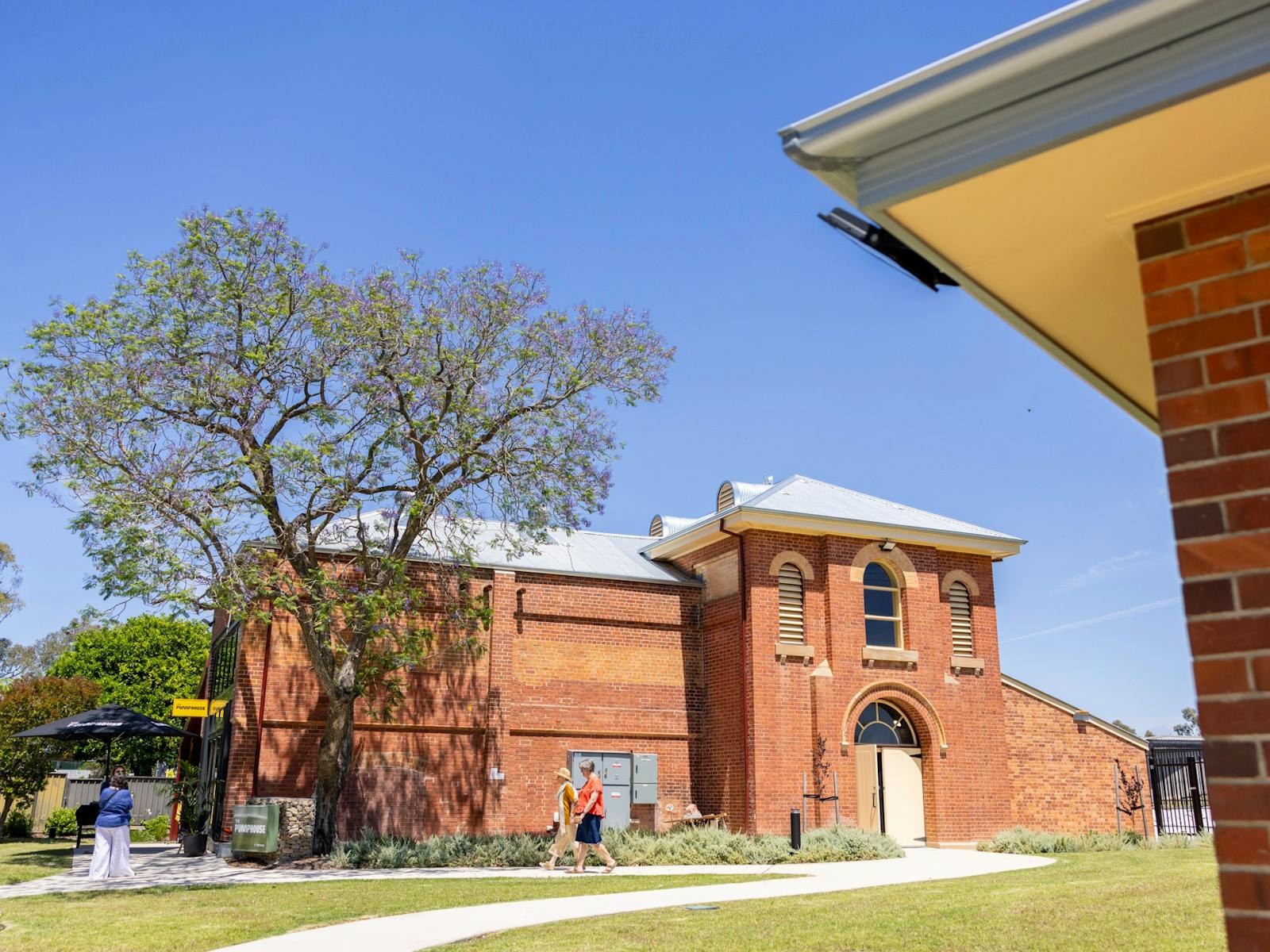 Exterior of old red brick building with a blue sky and arched windows