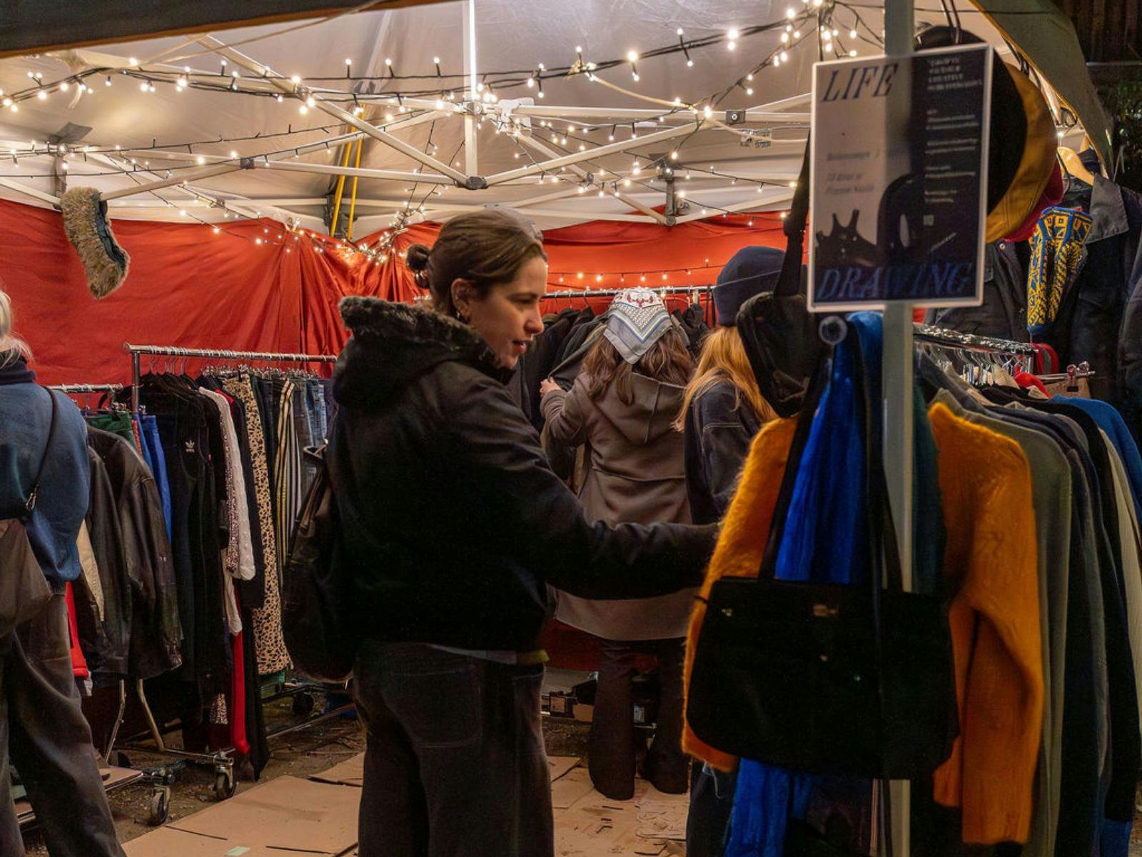A person looks at vintage clothing at CERES Winter Twilight Market