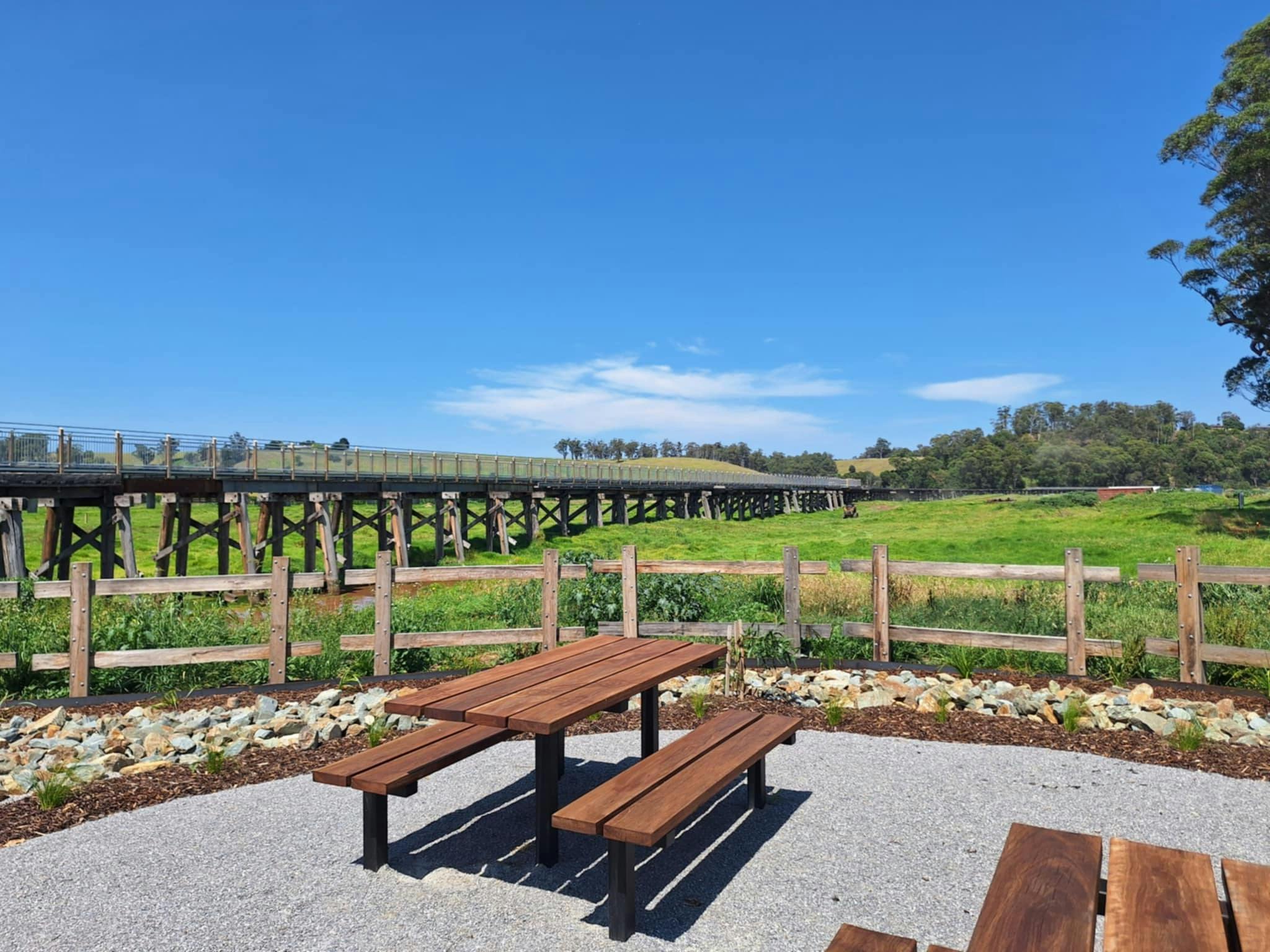 A picnic table in landscaped area with views across to the Snowy Rail Bridge