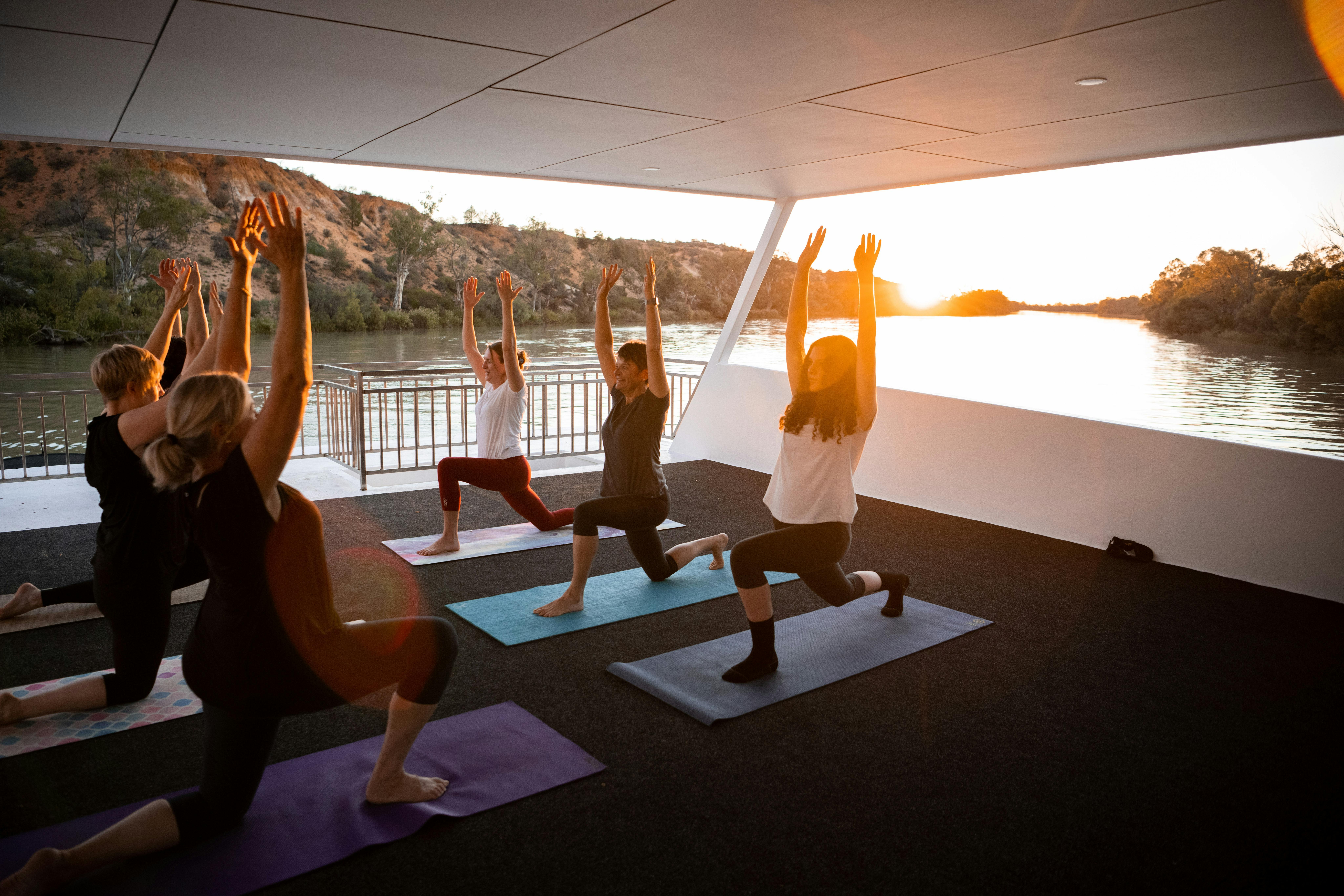 A group of people do yoga at sunset on the houseboat