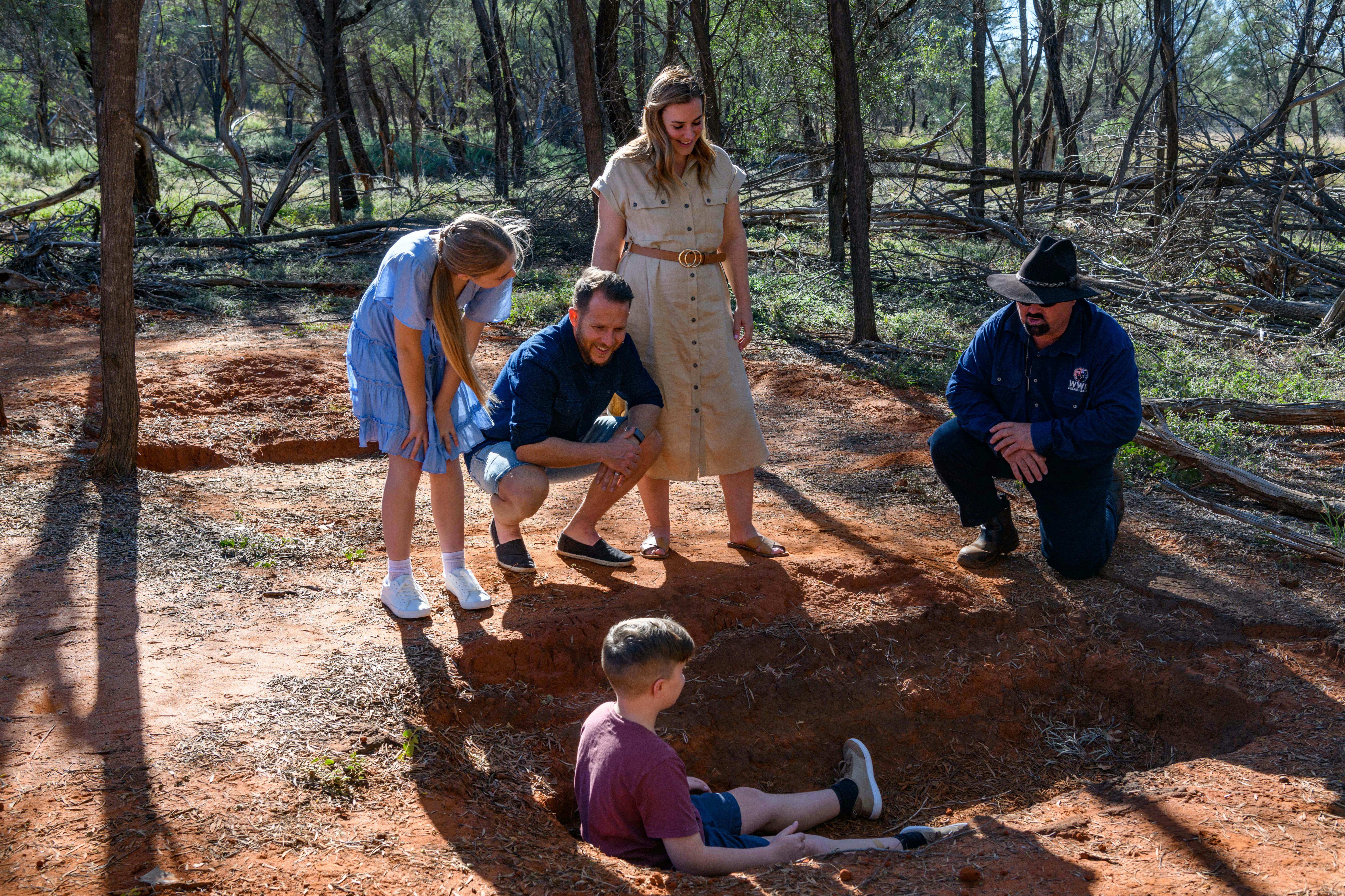 a family on tour with our guide out in the Mulga inspecting what remains of the bitumen baths