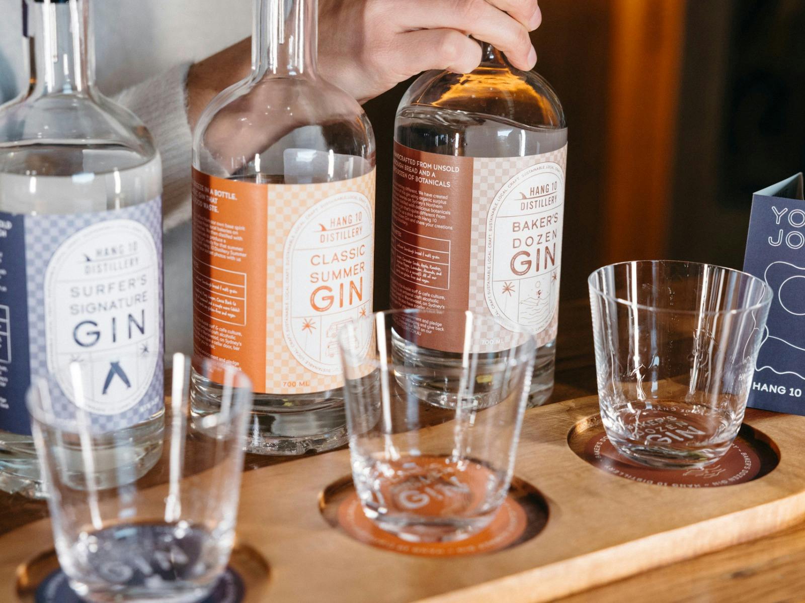 Three bottles of gins in front of a tasting paddle