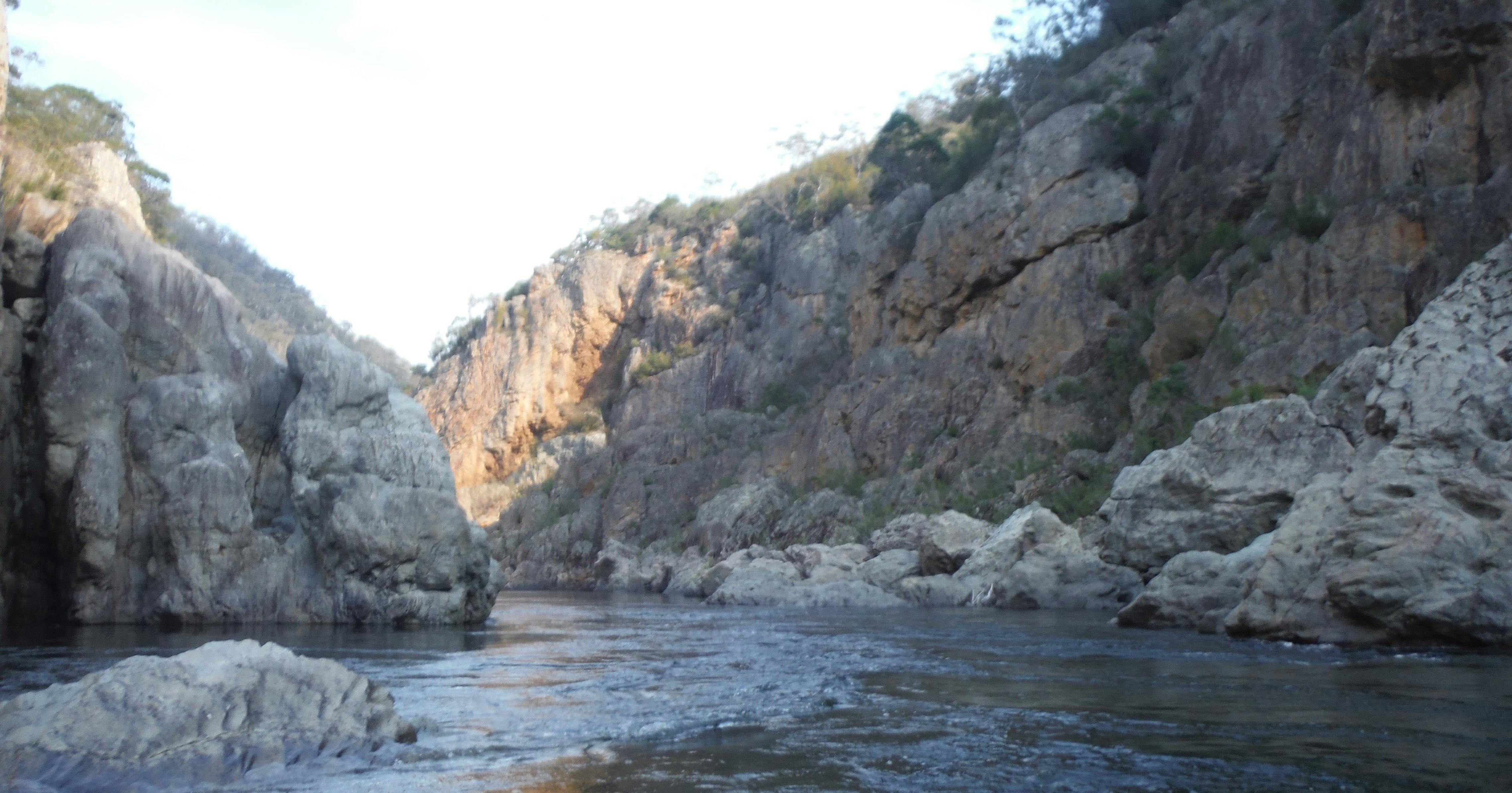 the snowy river is meandering around a huge rock at the entrance to a gorge