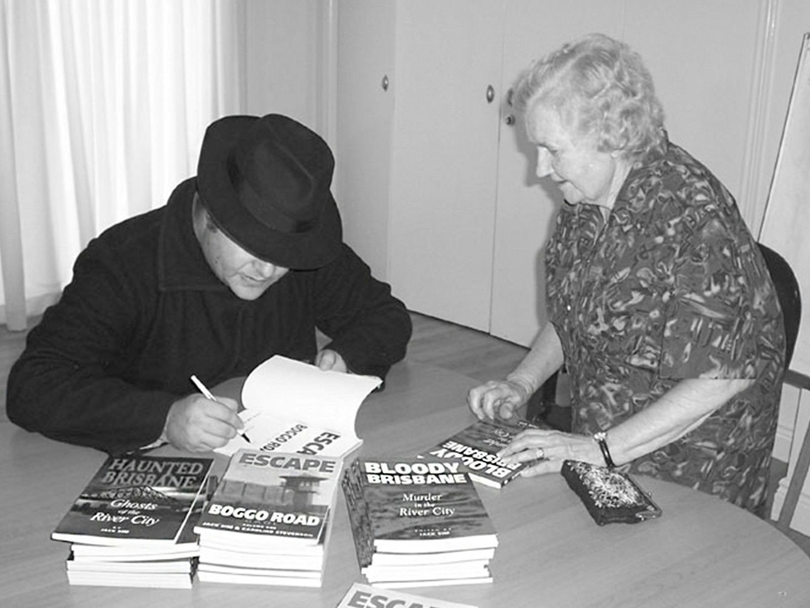 Jack Sim signing a book for an elderly customer