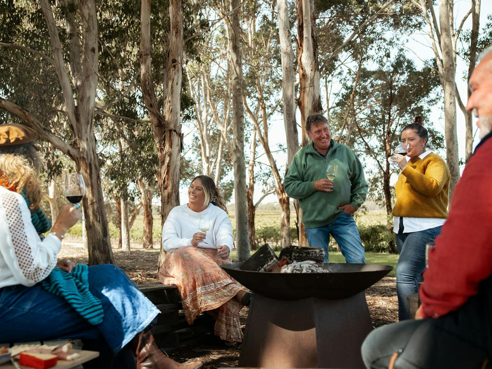 People sitting around a fire pit enjoying a glass of wine