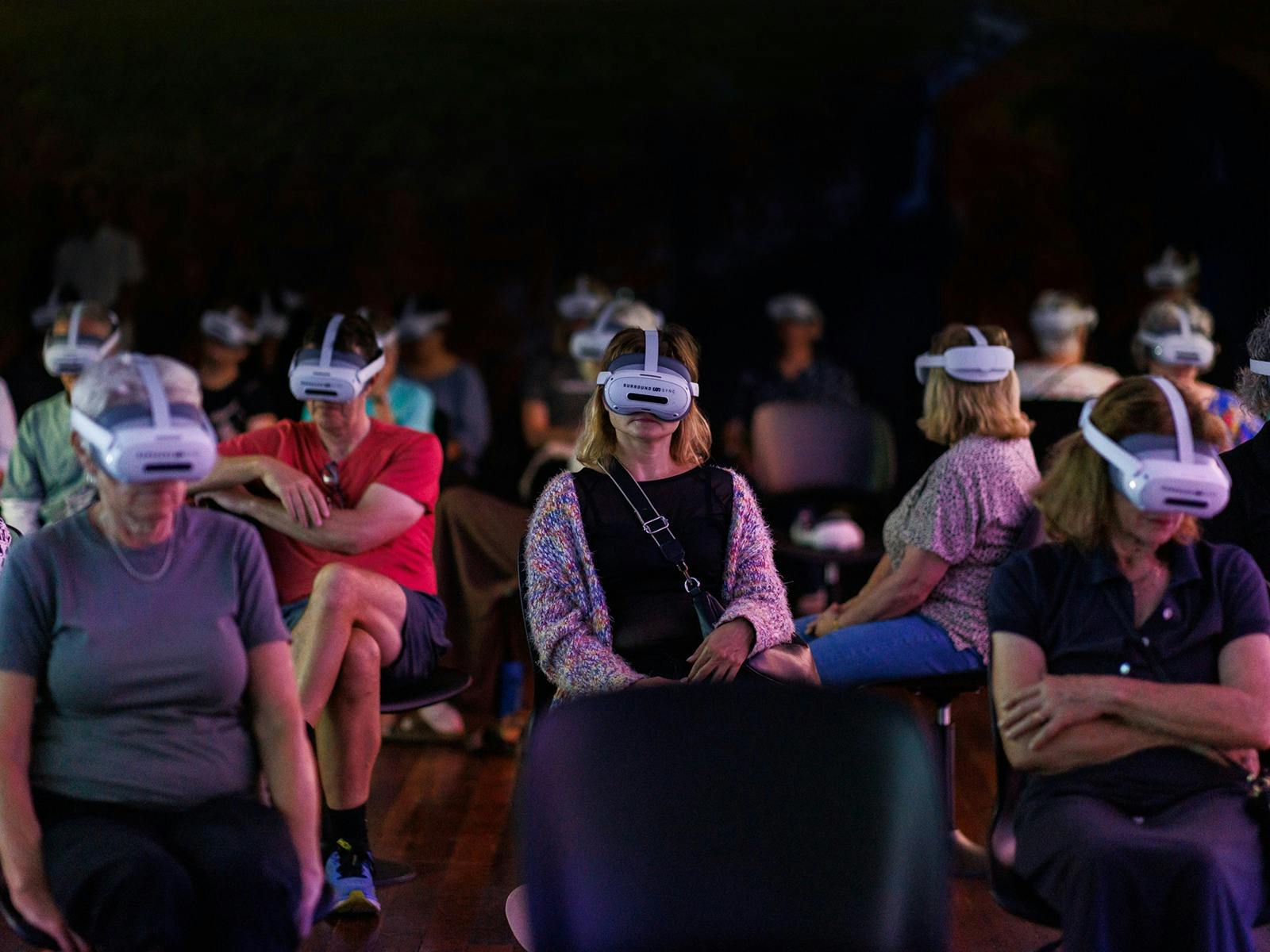 crowd wearing VR headsets setting on swivel chairs
