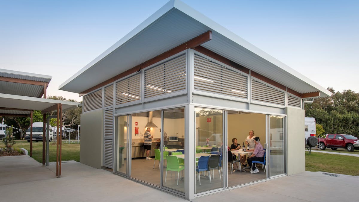 Shot of Mudjimba Beach Holiday Park camp kitchen with people drinking beer and cooking