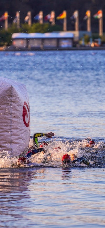 Swimmers swimming around course buoy