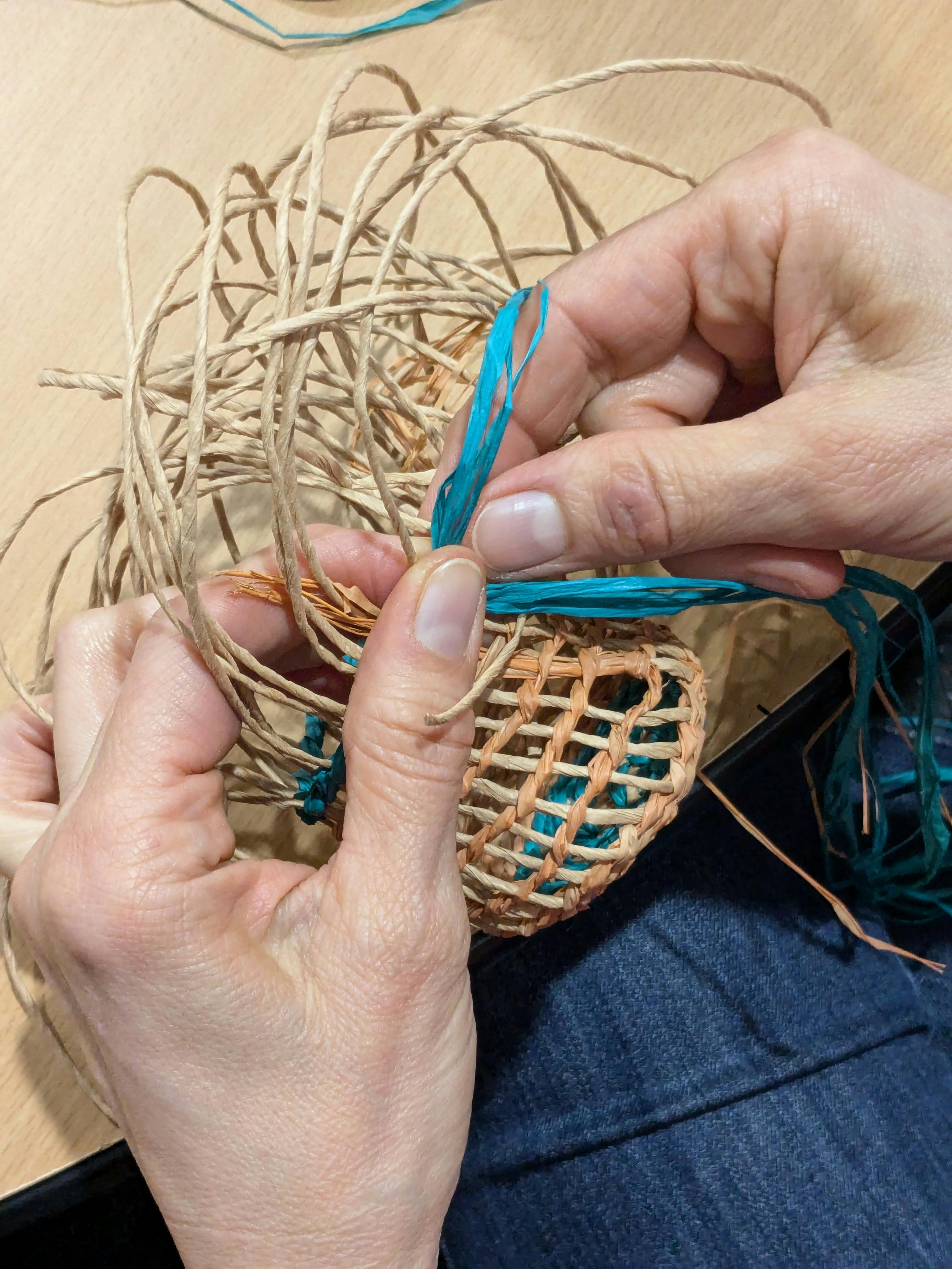 Close up of hands weaving a dilly bag