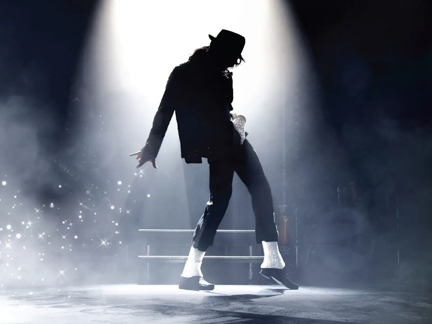 A male dancer wearing black suit and hat posing on the stage.