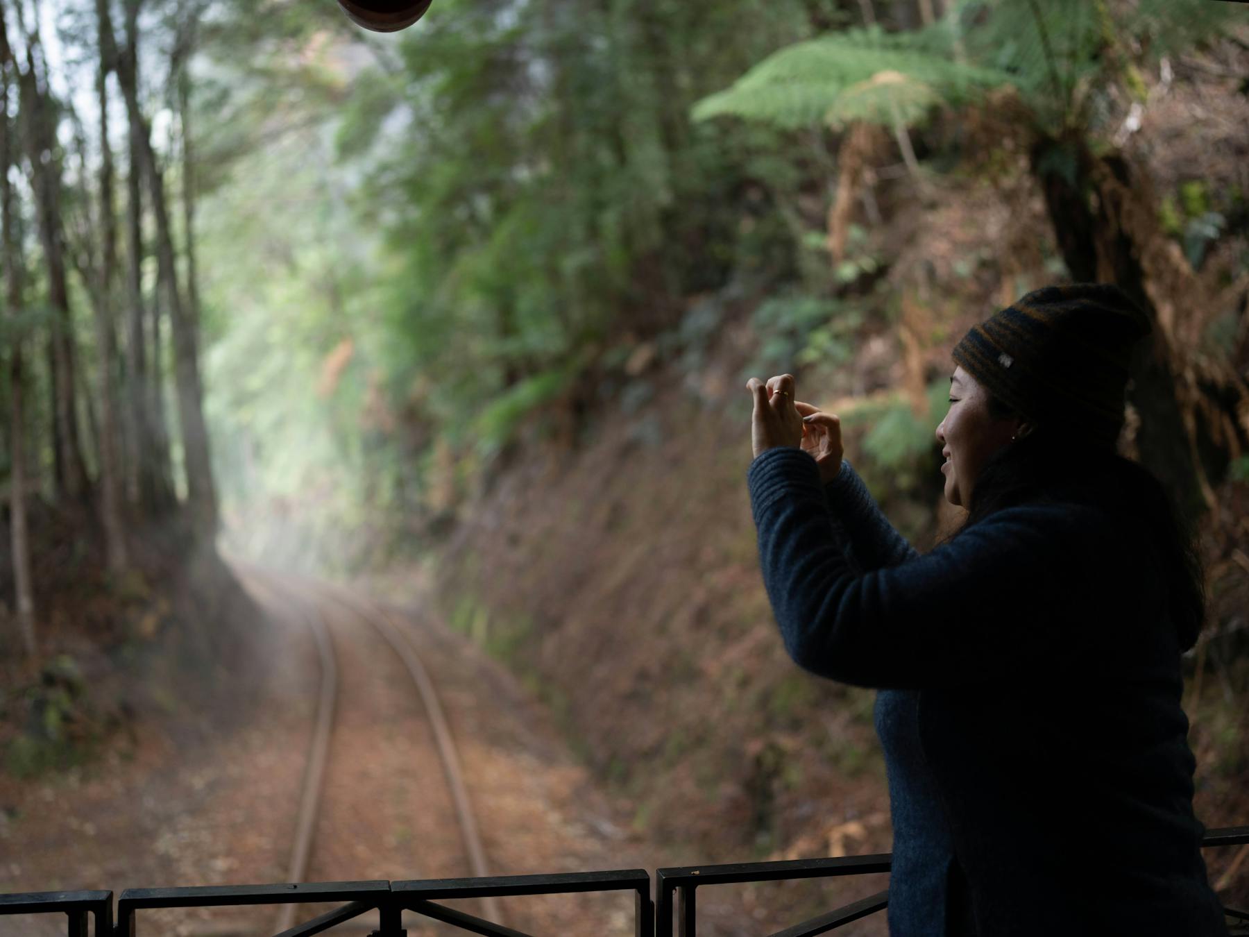 Woman stands on wilderness carriage balcony to take photos