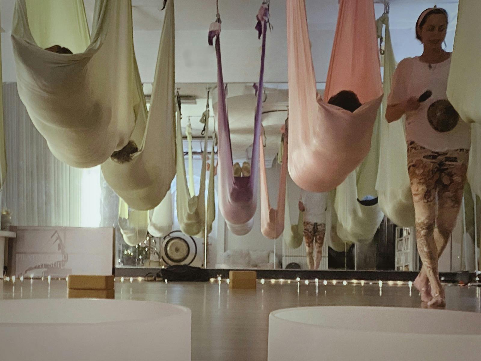 Image of people resting in hammocks while Natalie walks around playing a singing bowl.