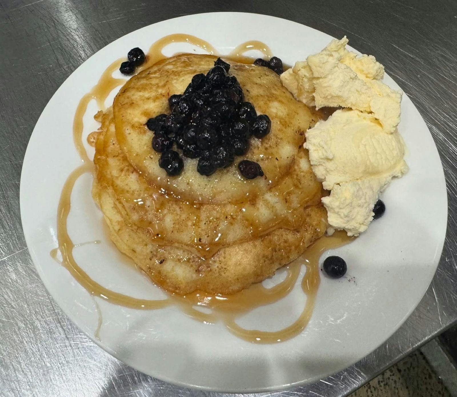 Hotcakes Stack with berries and ice cream sitting on a plate at Vode Cafe