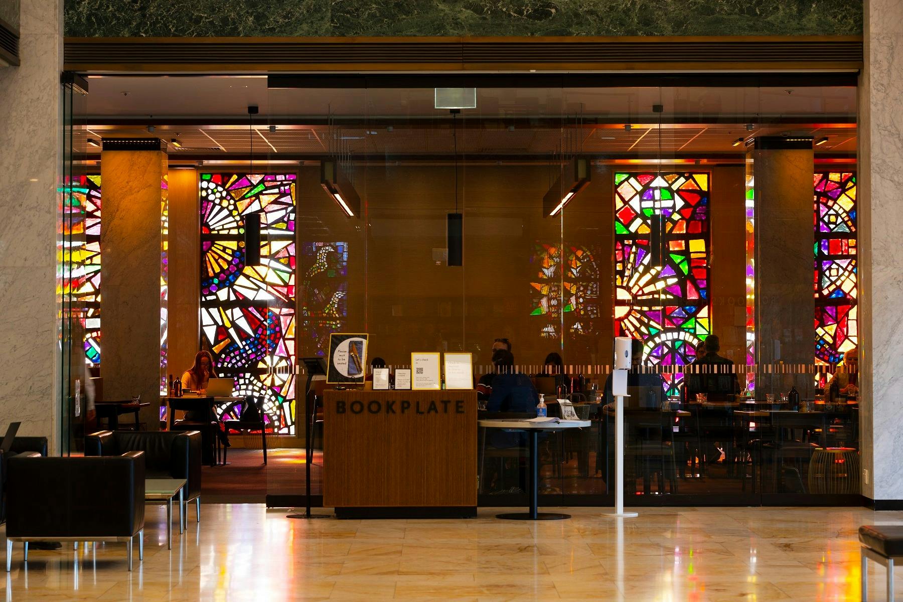 The front glass doors of a cafe. There are stained glass windows on the back wall of the cafe.