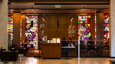 The front glass doors of a cafe. There are stained glass windows on the back wall of the cafe.
