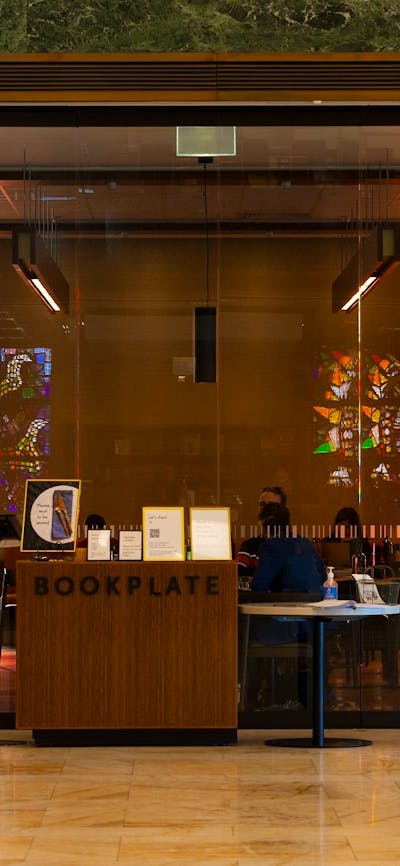 The front glass doors of a cafe. There are stained glass windows on the back wall of the cafe.