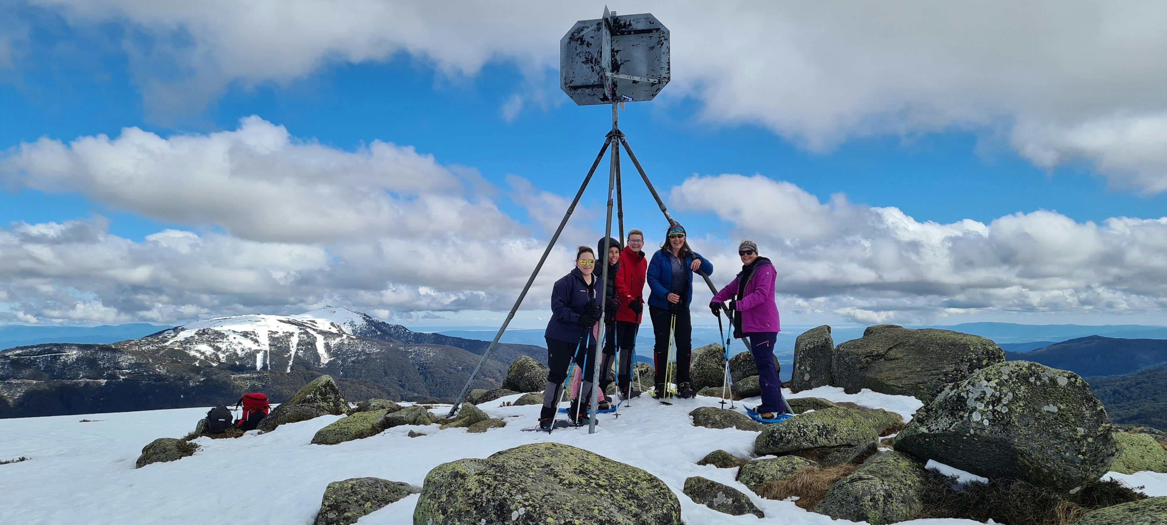 A group of hikers on the summit of Mt Stirling with Mt Buller in the background.