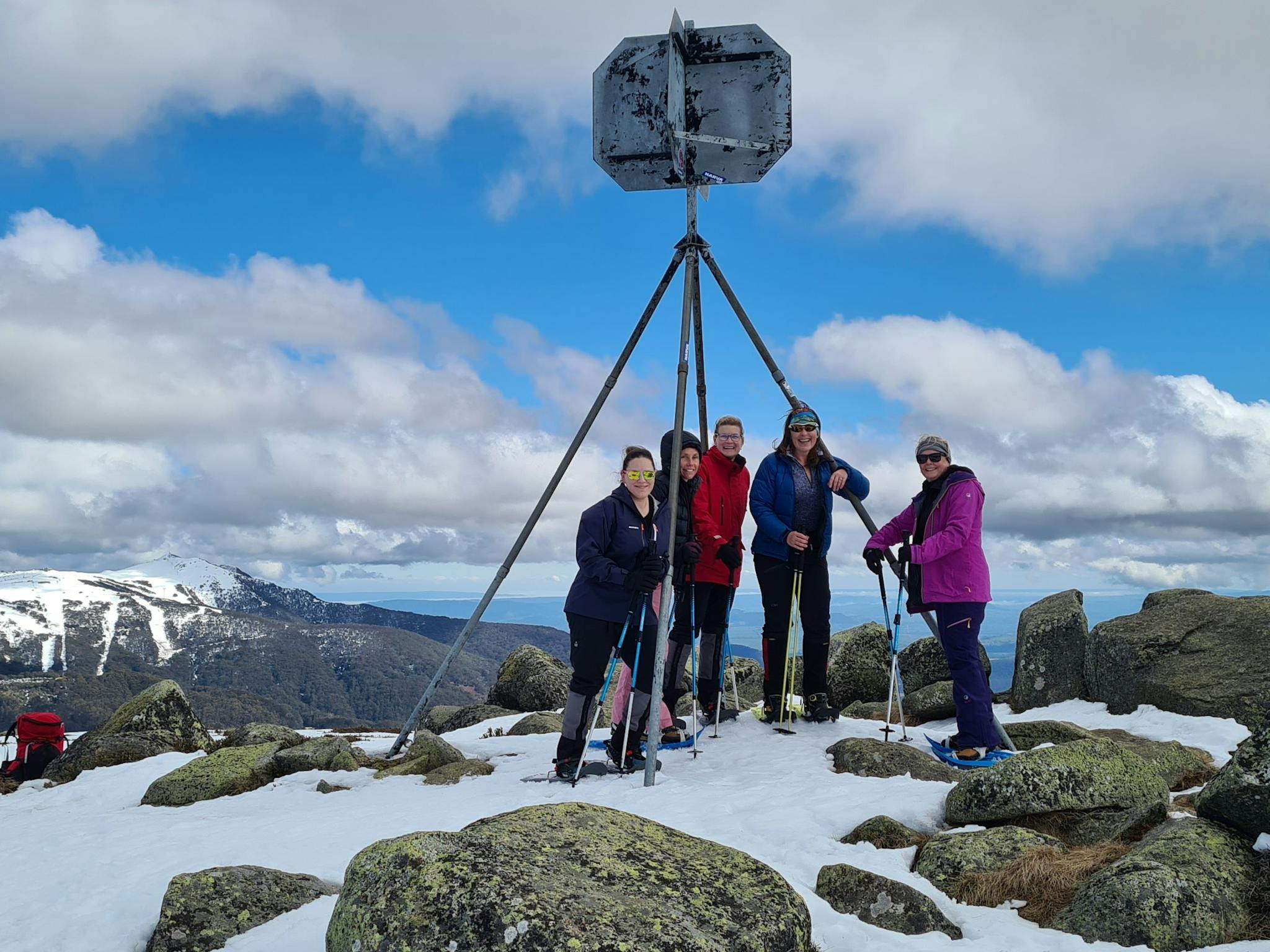 A group of hikers on the summit of Mt Stirling with Mt Buller in the background.