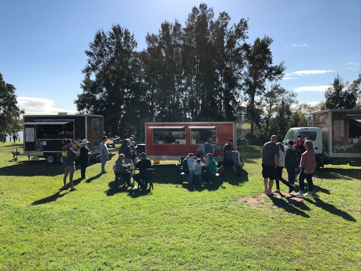 People queue for food in the sun from food trucks at Queens Wharf Morpeth
