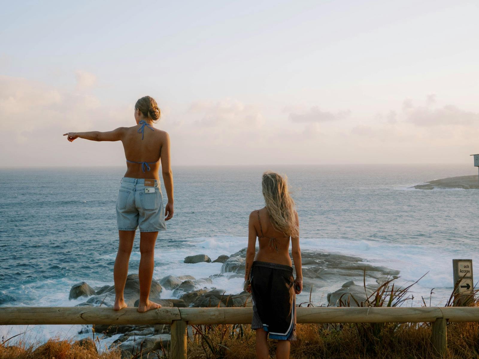 Two girls look out over the beach at sunset Two girls look out over the beach at sunset