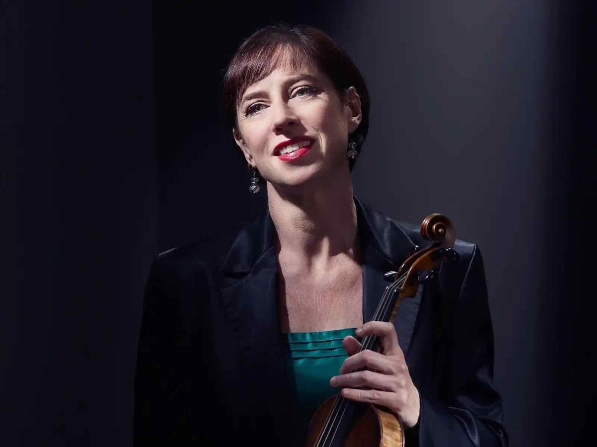 Madeleine Easton suits against a black background with a violin