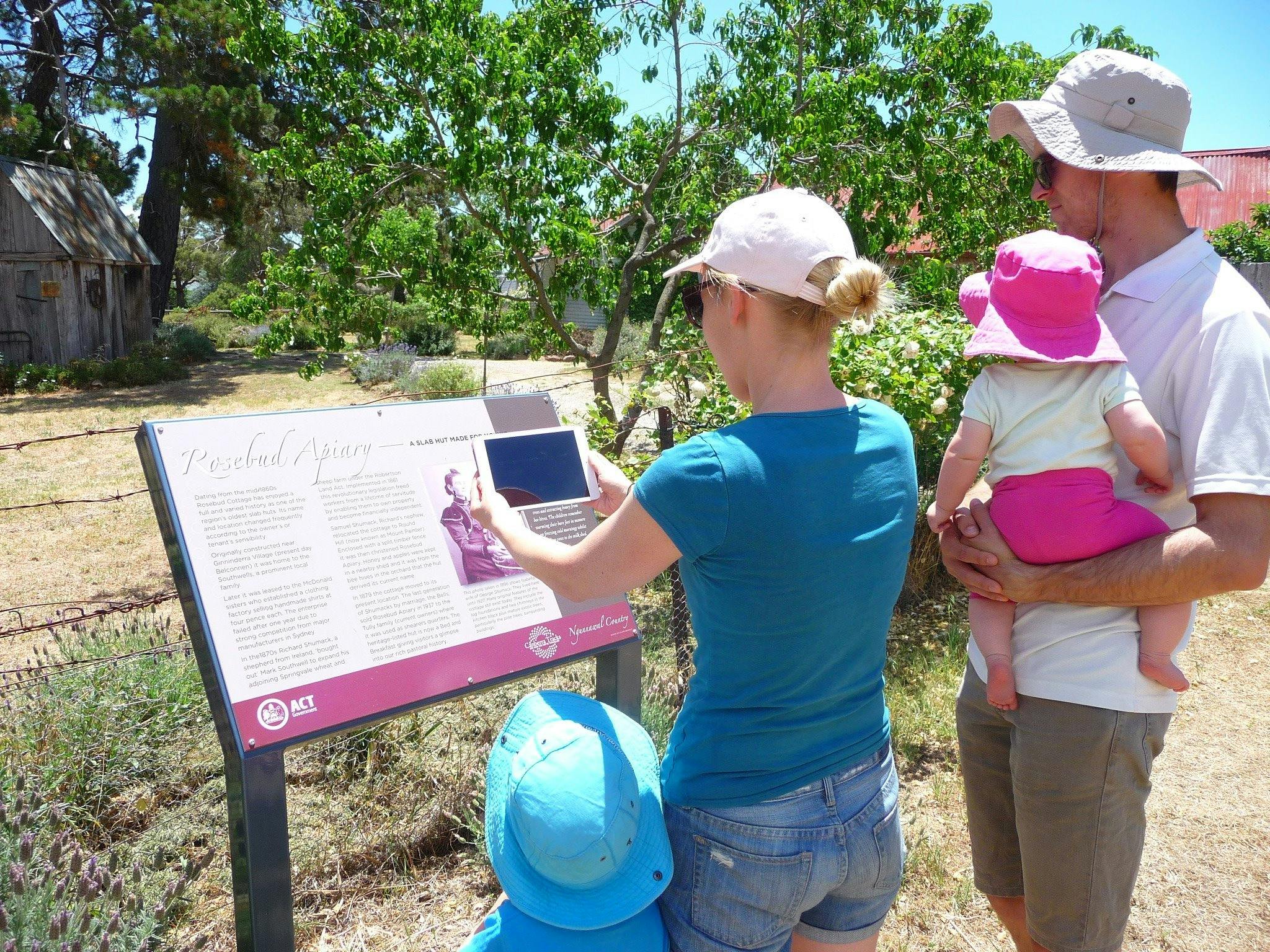 Two adults and two children looking at information panel outdoors