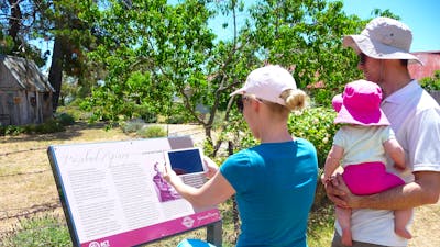 Two adults and two children looking at information panel outdoors