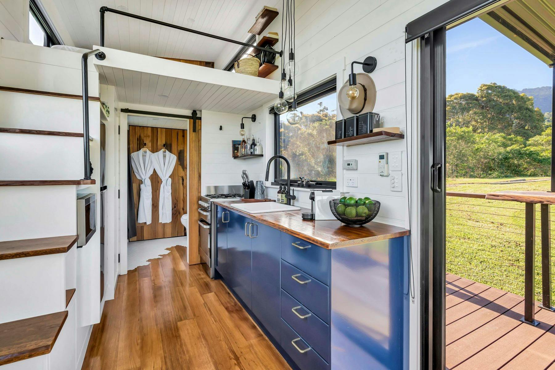 작은 집 문송의 내부 이미지. 문에 두 개의 가운이 걸려 있습니다. 작은 주방이 보입니다.