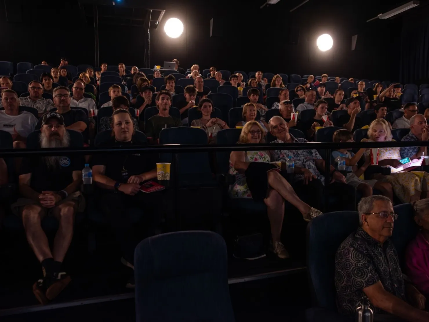 Crowded theater awaiting filming people looking at screen and smiling