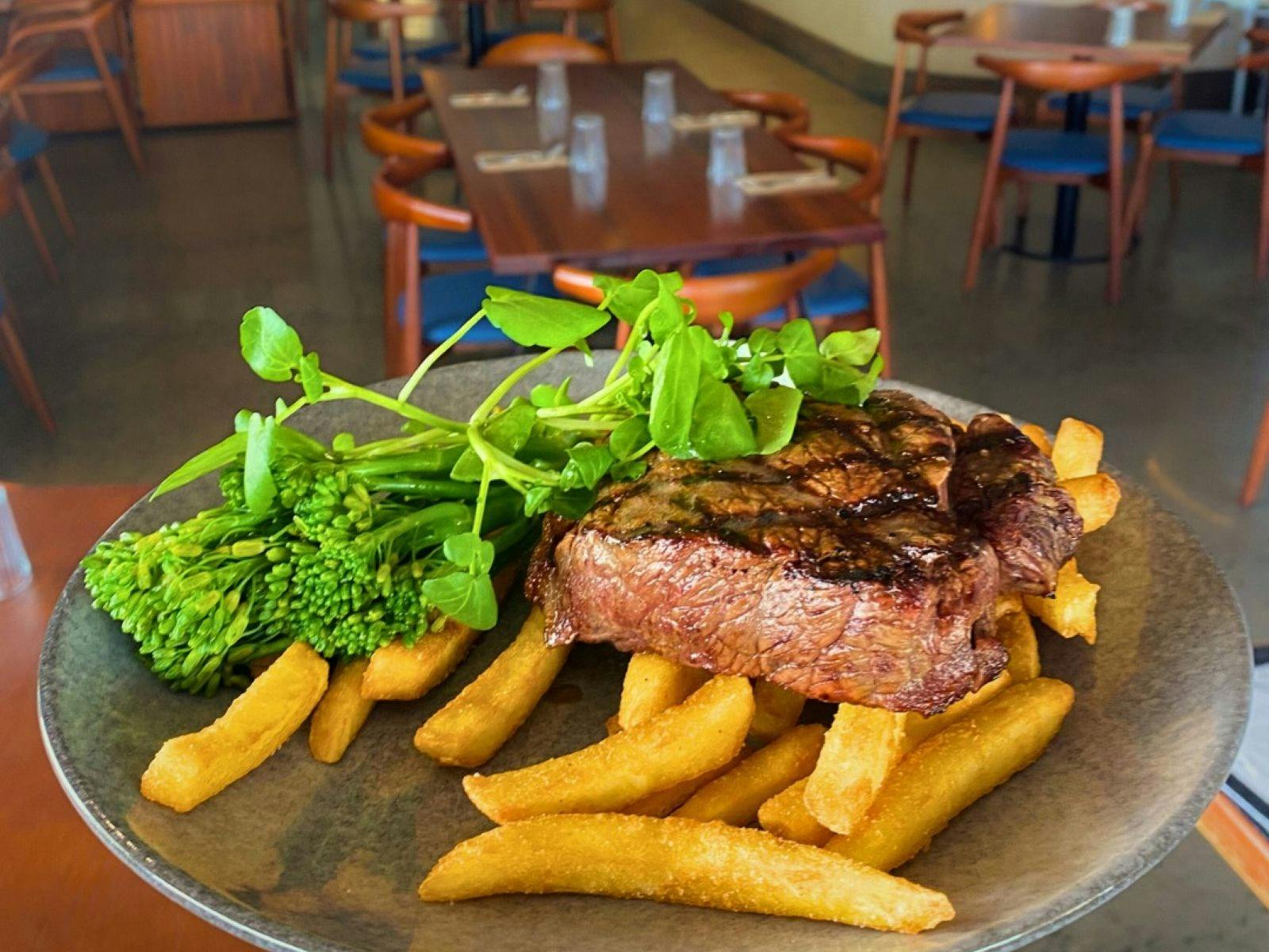 Steak, chips and broccolini on a plate