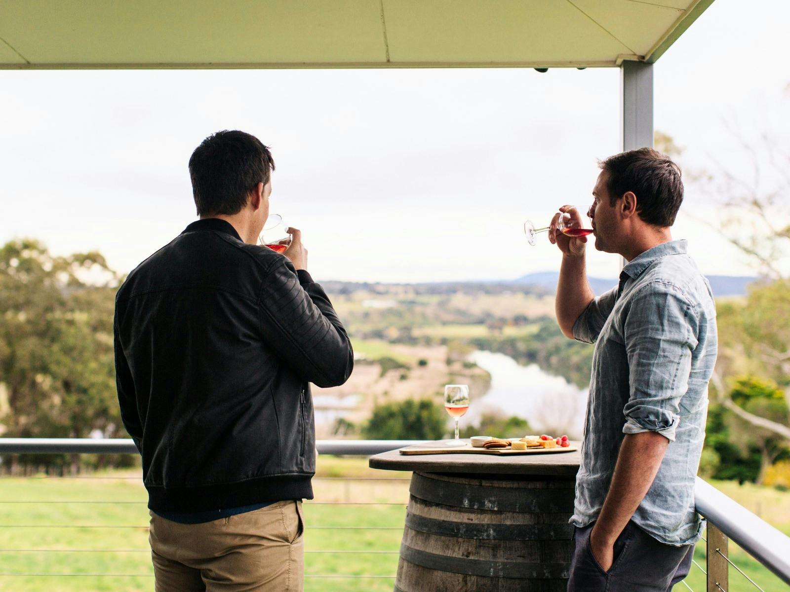 Two men drinking wine and enjoying a cheeseboard while enjoying the landscape