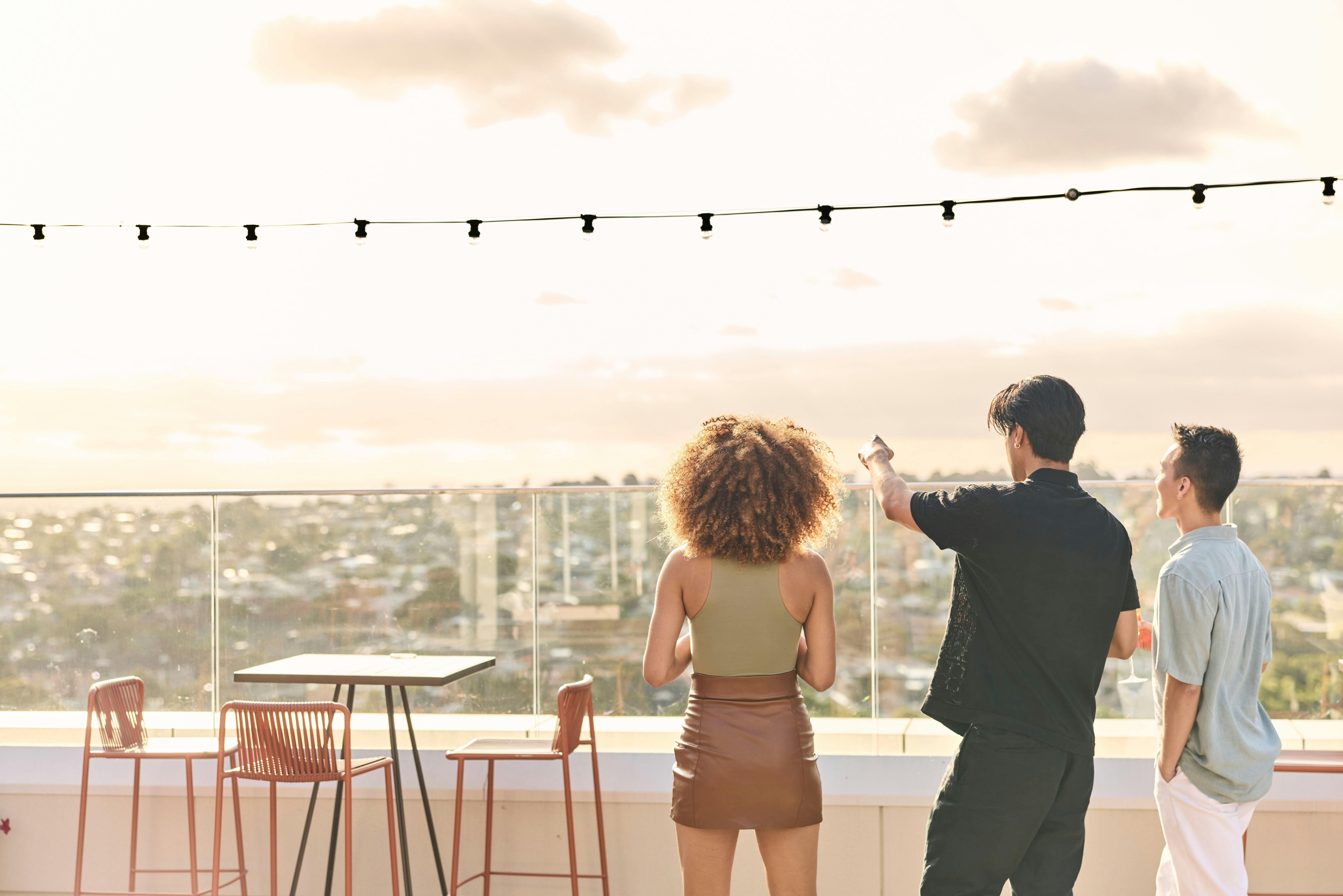 Three friends looking at pointing at view on balcony