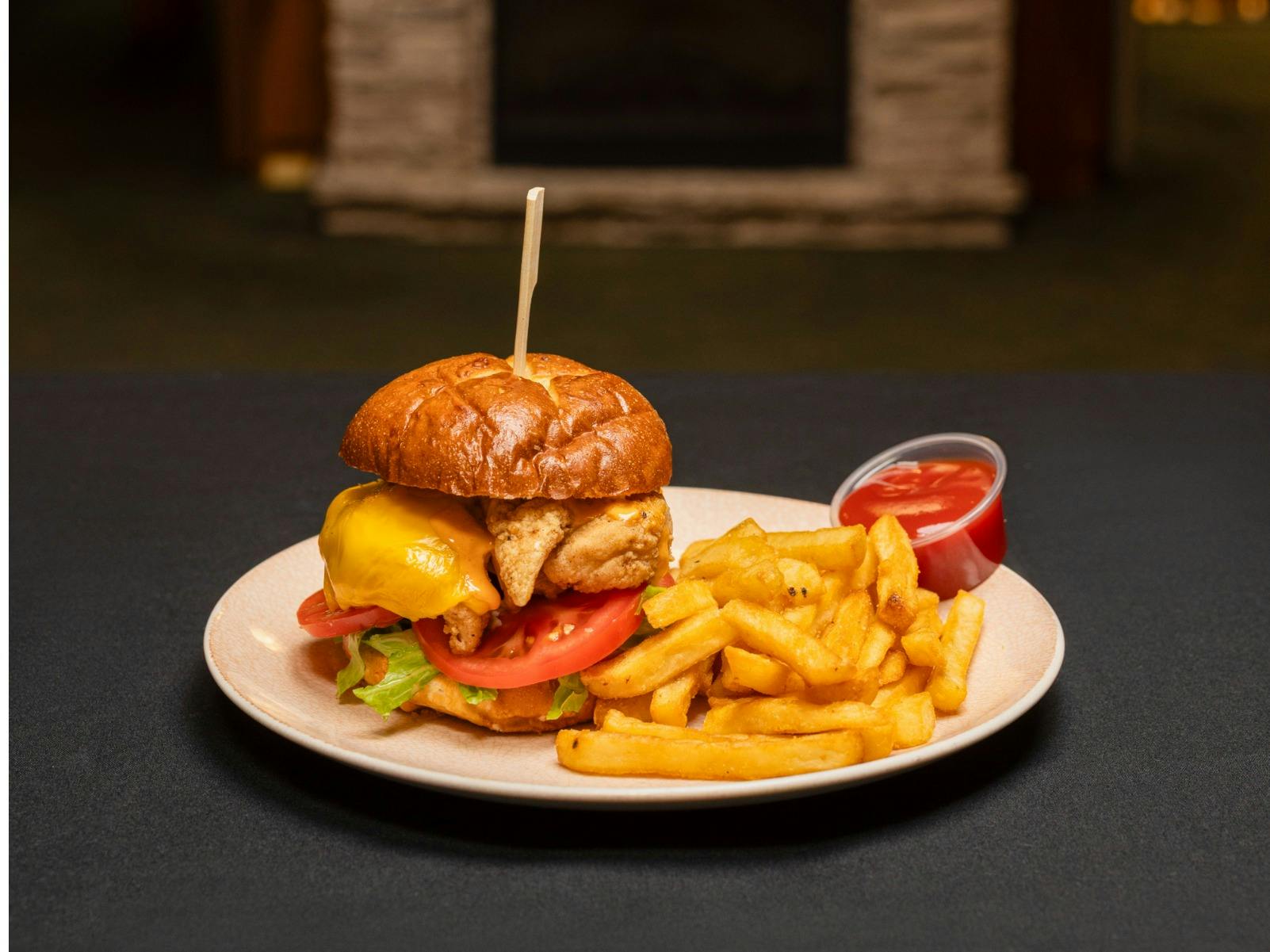 Buttermilk soaked chicken tenders, lettuce, tomato, cheese, tangy burger sauce on a pretzel bun