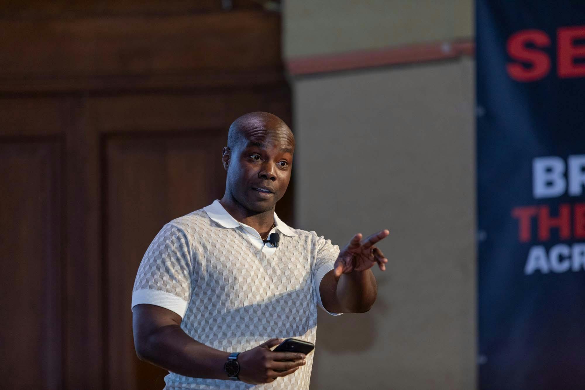 A man in a white shirt talking on stage.