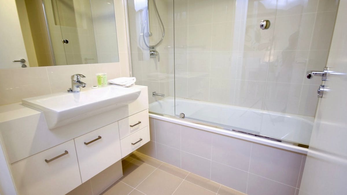 Private bathroom with bathtub, glass shower screen, floating vanity and tiled floors at Domain Servi