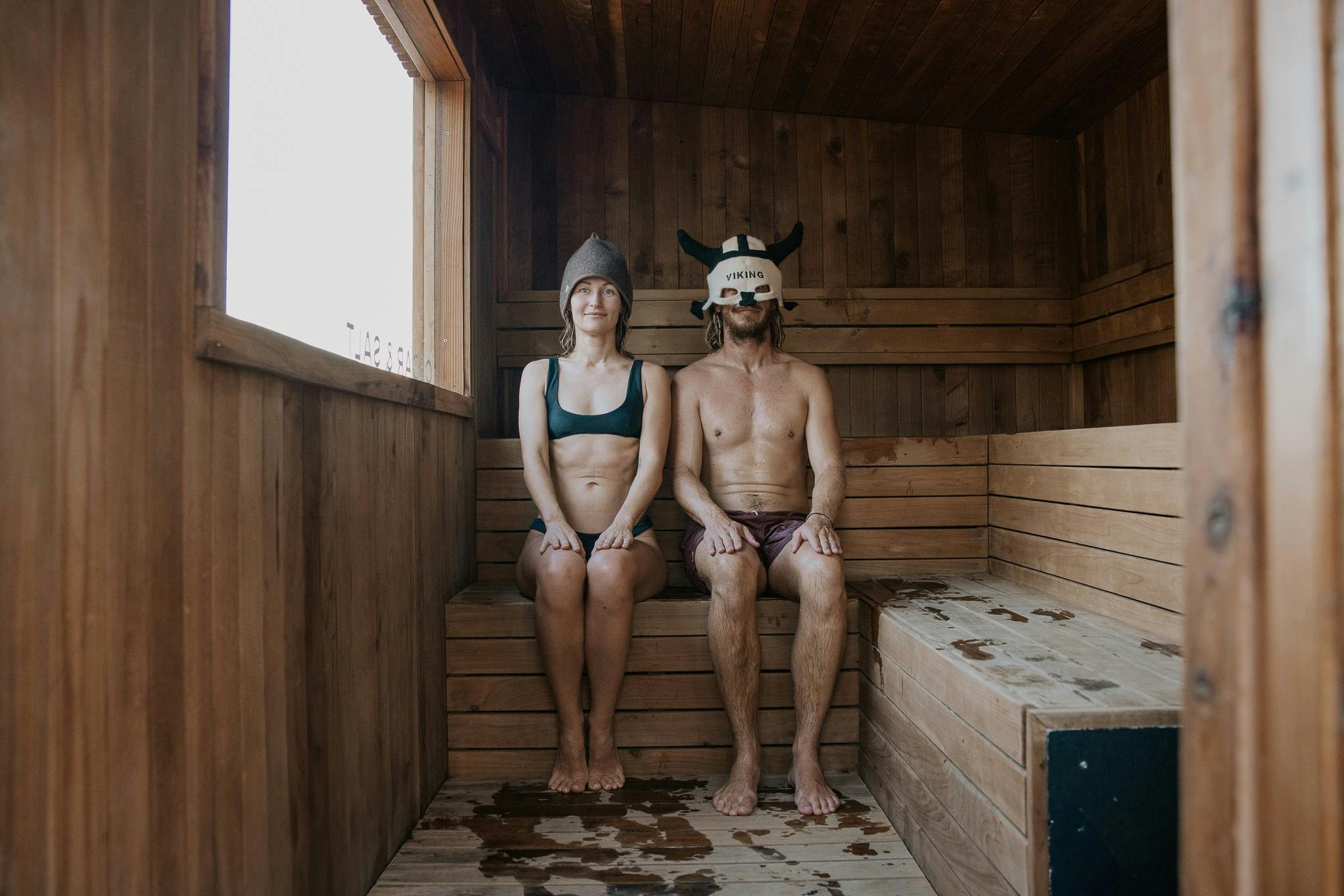 2 friends in a sauna wearing sauna hats