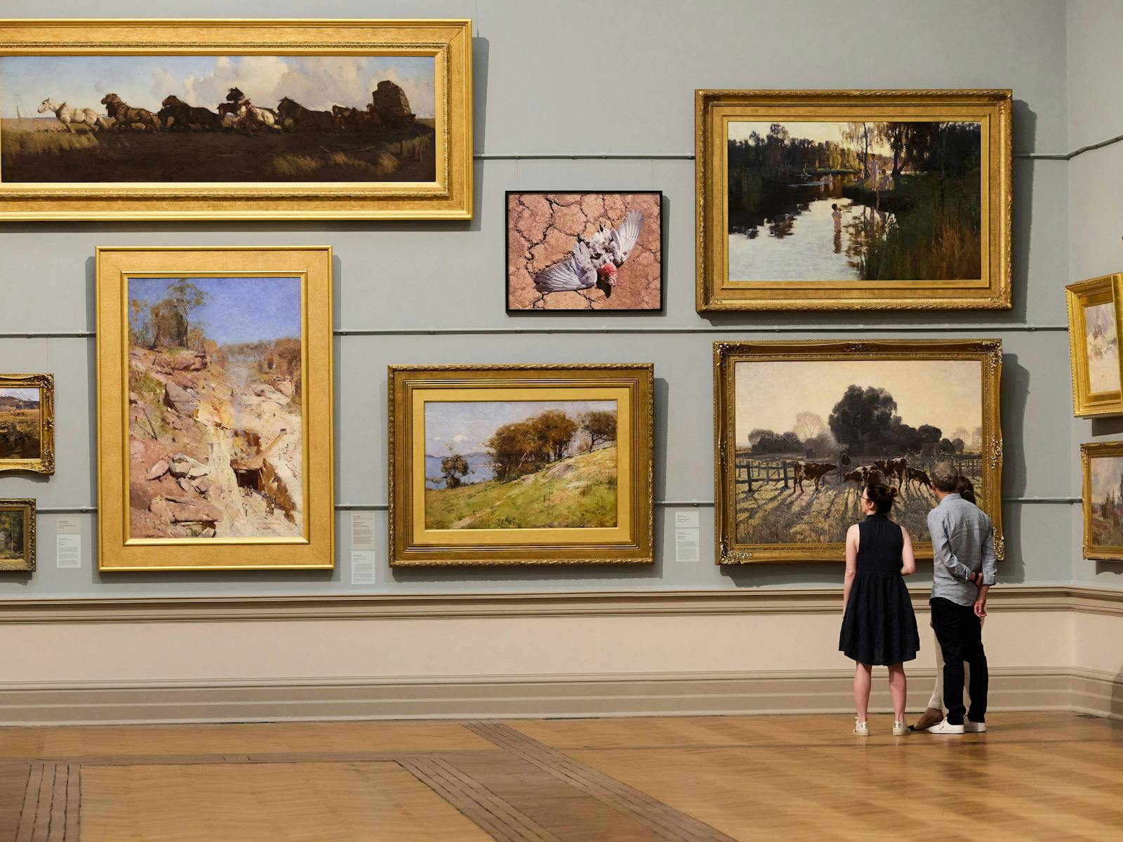 A couple of people looking at paintings on a wall