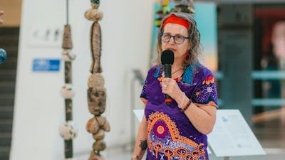 Woman dressed in aboriginal polo shirt standing in front of stone sculptures