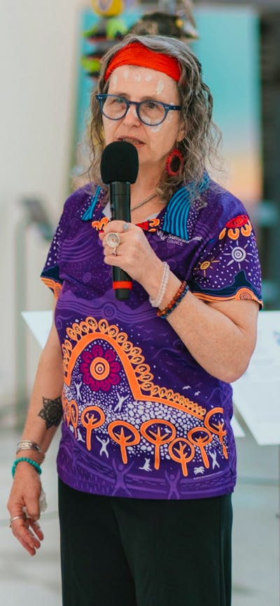 Woman dressed in aboriginal polo shirt standing in front of stone sculptures