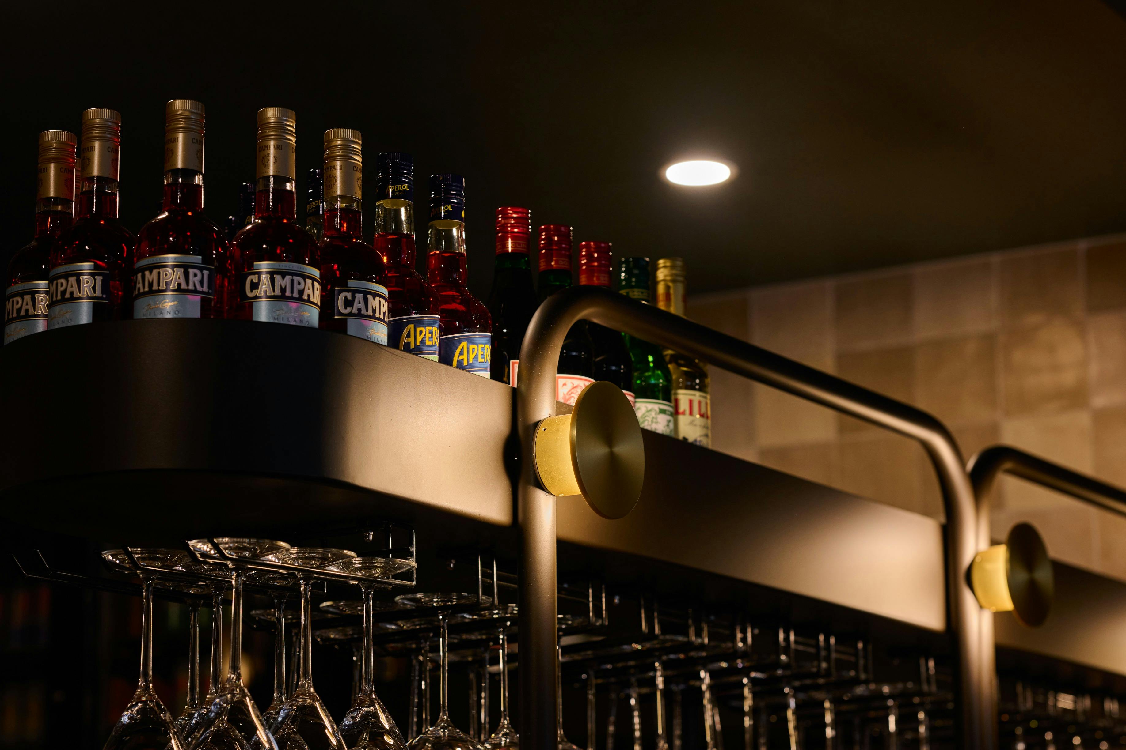 Shop details, black shelf storing liquor on top, wine glasses beneath