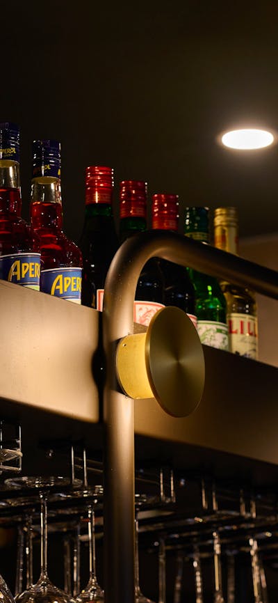 Shop details, black shelf storing liquor on top, wine glasses beneath